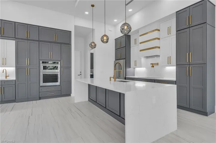 Kitchen featuring appliances with stainless steel finishes, gray cabinetry, and pendant lighting