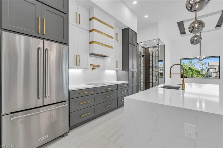 Kitchen featuring stainless steel fridge, gray cabinetry, black electric cooktop, sink, and white cabinets