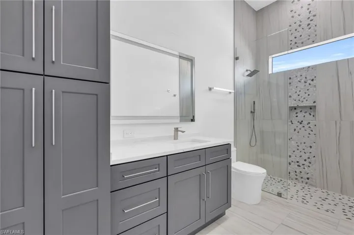 Bathroom featuring vanity, walk in shower, and toilet