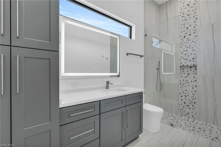 Bathroom with vanity, tiled shower, and toilet