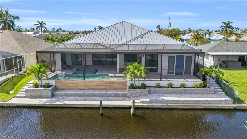 Rear view of house featuring glass enclosure, a water view, and a patio area