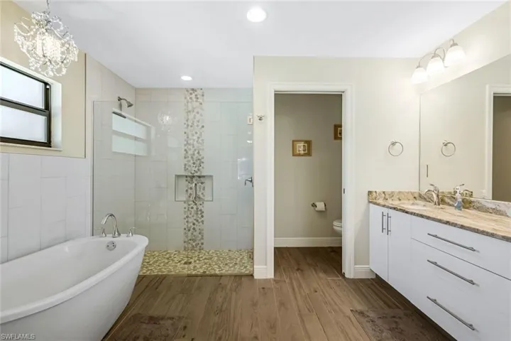 Full bathroom with vanity, toilet, wood-type flooring, and plus walk in shower