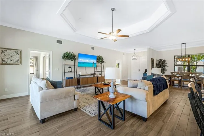 Living room with hardwood / wood-style floors, ceiling fan with notable chandelier, and ornamental molding
