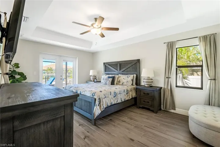 Bedroom with a raised ceiling, multiple windows, and wood-type flooring