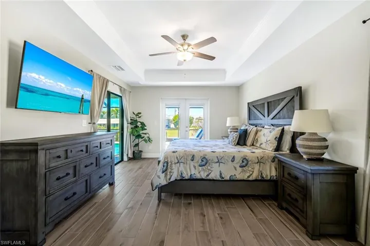 Bedroom featuring hardwood / wood-style flooring, ceiling fan, and a tray ceiling