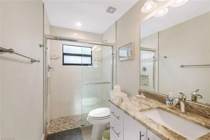 Bathroom featuring hardwood / wood-style floors, vanity, toilet, and a shower with shower door