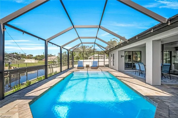 View of pool with glass enclosure and a patio area