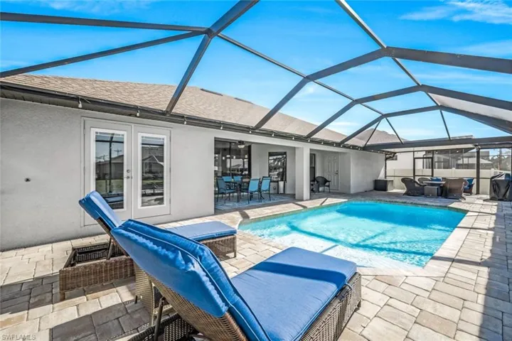 View of swimming pool featuring glass enclosure, ceiling fan, and a patio area
