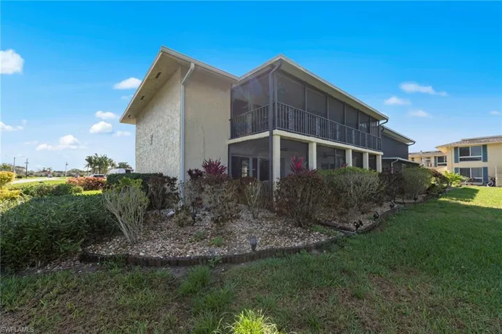 Rear view of property with a sunroom, a lawn, and a balcony