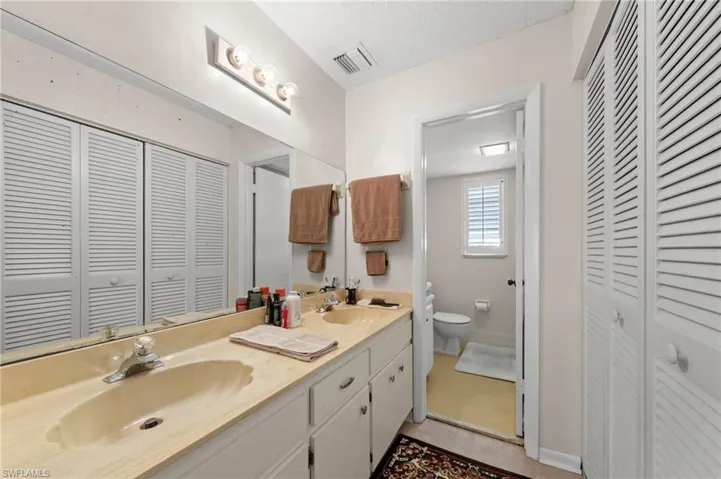 Bathroom with a closet, double vanity, and a textured ceiling
