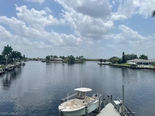 Waterfront property featuring a private boat dock with lift, direct canal access, and mature palm trees