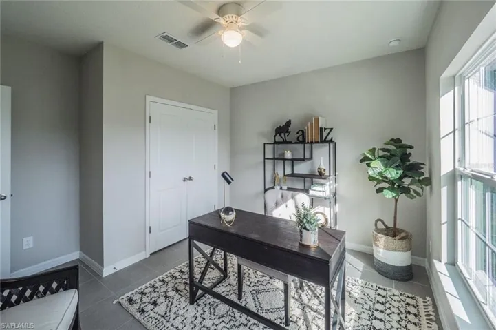 Tiled office space featuring a ceiling fan and baseboards