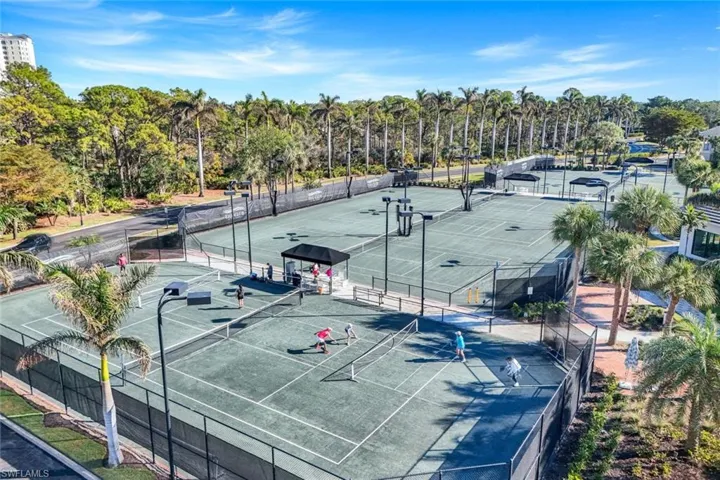 View of tennis court featuring view of wooded area and community basketball court