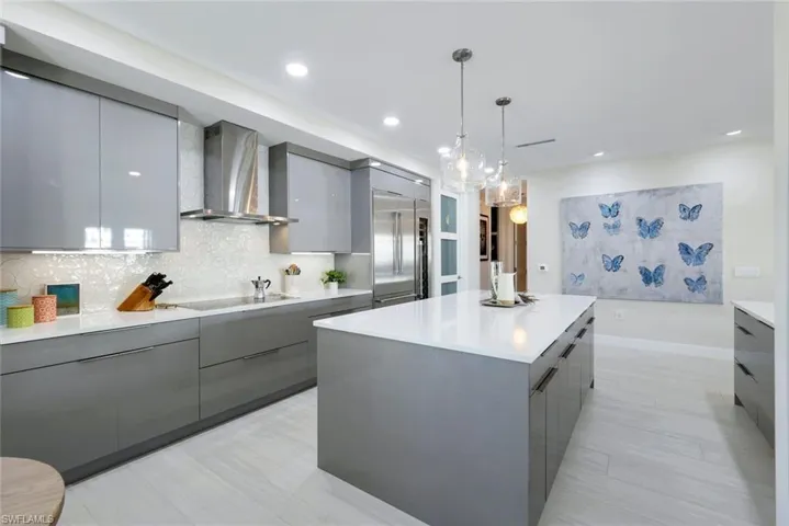 Kitchen featuring gray cabinets, modern cabinets, wall chimney exhaust hood, a center island, and recessed lighting