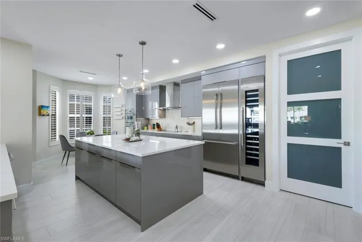 Kitchen with gray cabinets, modern cabinets, decorative light fixtures, a kitchen island, and stainless steel built in refrigerator