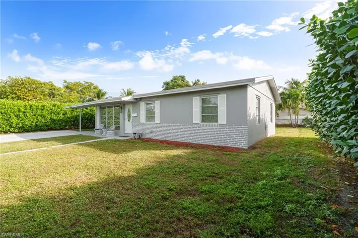 View of front facade with a front lawn, brick siding, stucco siding, and a carport