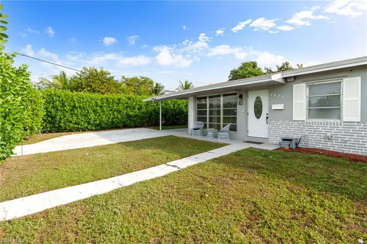 View of grassy yard with an attached carport and driveway