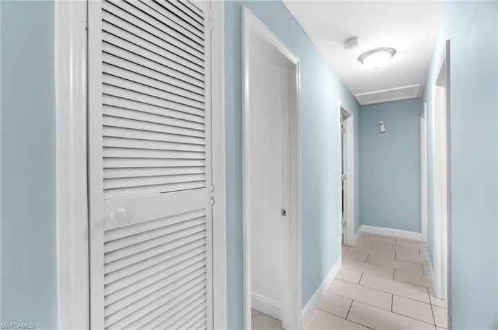 Corridor featuring light tile patterned floors and attic access