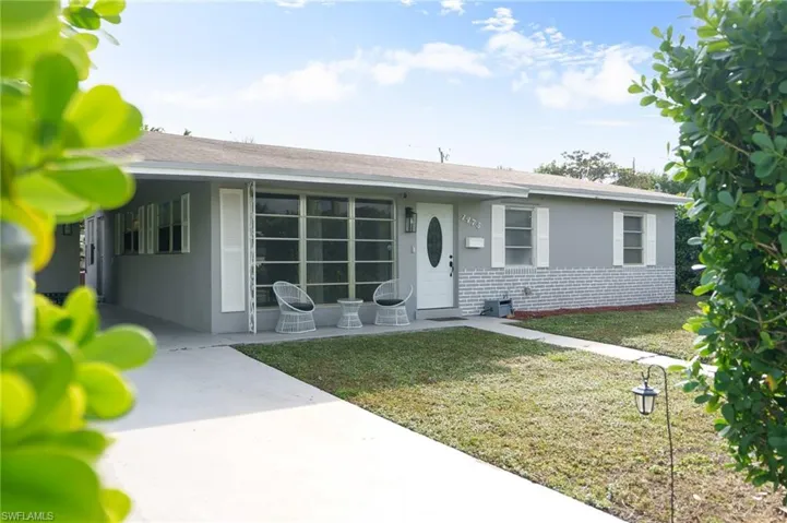 Ranch-style house with brick siding, a front lawn, stucco siding, and a shingled roof