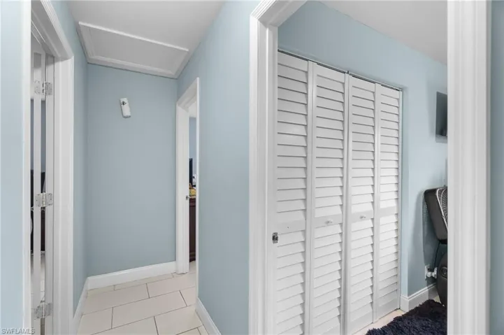 Corridor featuring light tile patterned floors and attic access
