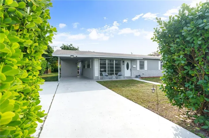Single story home featuring a front yard, brick siding, concrete driveway, an attached carport, and stucco siding