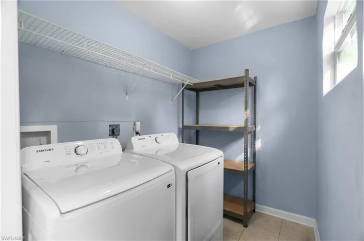Washroom with light tile patterned floors and washing machine and clothes dryer