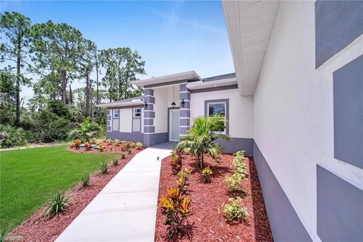 Doorway to property with a lawn and stucco siding