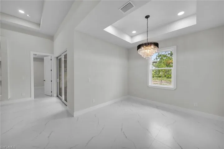 Spare room featuring baseboards, visible vents, marble finish floor, and a tray ceiling