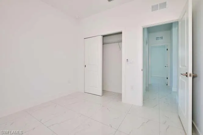 Unfurnished bedroom featuring light marble finish floors and a closet