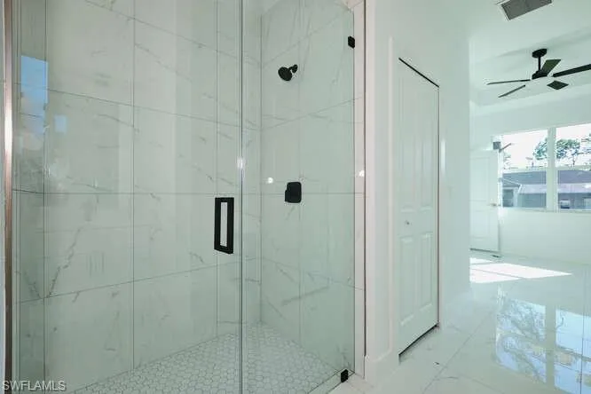 Bathroom with a marble finish shower and ceiling fan