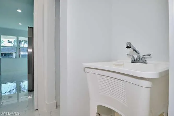Bathroom featuring vanity, light marble finish flooring, and recessed lighting