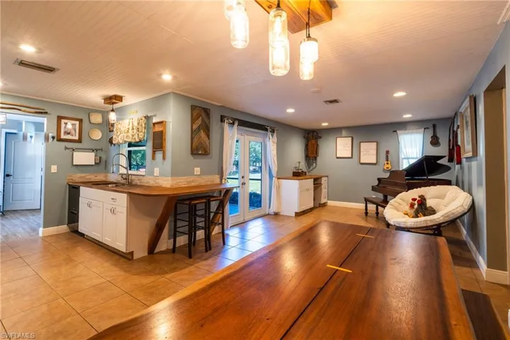 Kitchen with french doors, sink, hanging light fixtures, a healthy amount of sunlight, and white cabinets