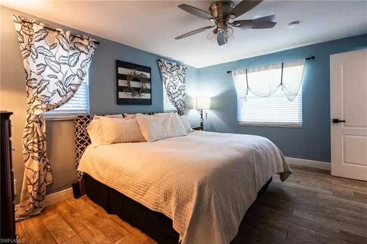Bedroom with ceiling fan, hardwood / wood-style floors, and multiple windows