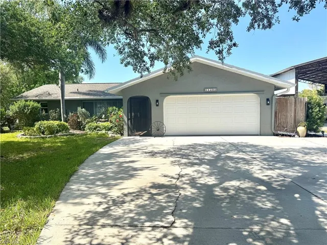Ranch-style home featuring driveway, fence, an attached garage, stucco siding, and a front lawn