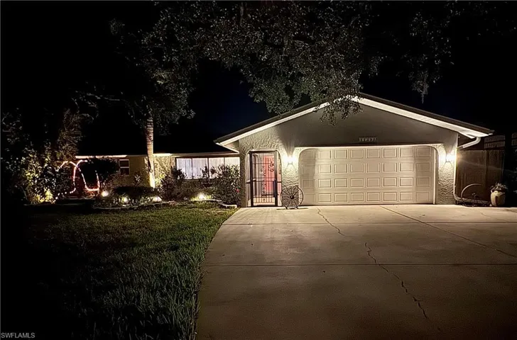 Ranch-style home featuring a garage, driveway, and a lawn