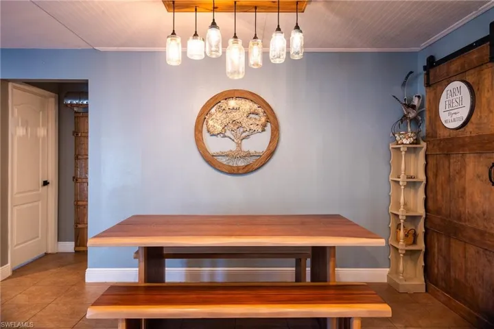 Unfurnished dining area featuring tile patterned flooring, crown molding, and a barn door