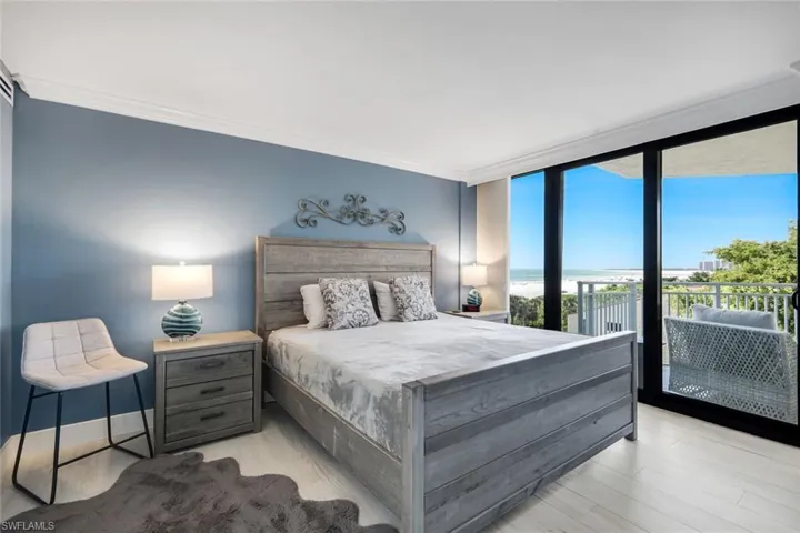 This room features a sliding glass door providing access to an outdoor balcony, with views of the ocean and trees