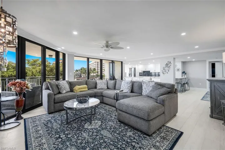 This expansive living area features light-colored flooring, recessed lighting, and a ceiling fan