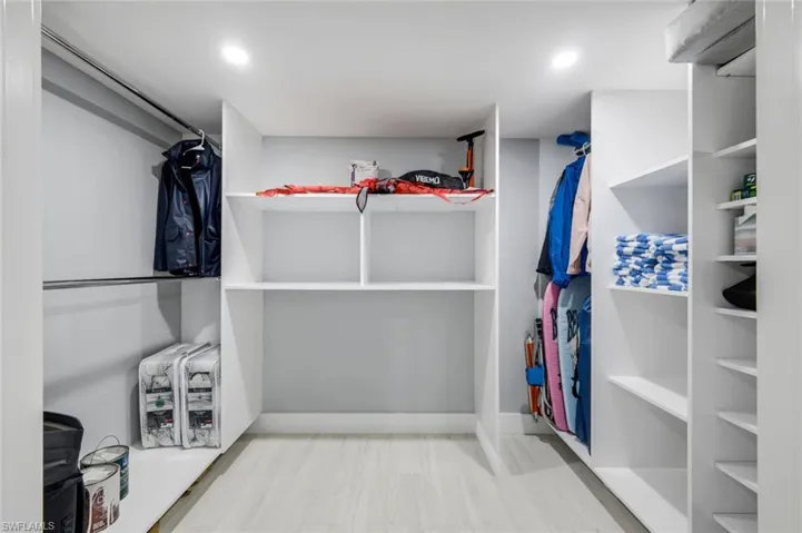 Walk-in closet featuring extensive built-in shelving and hanging rods, recessed lighting, and light-colored flooring
