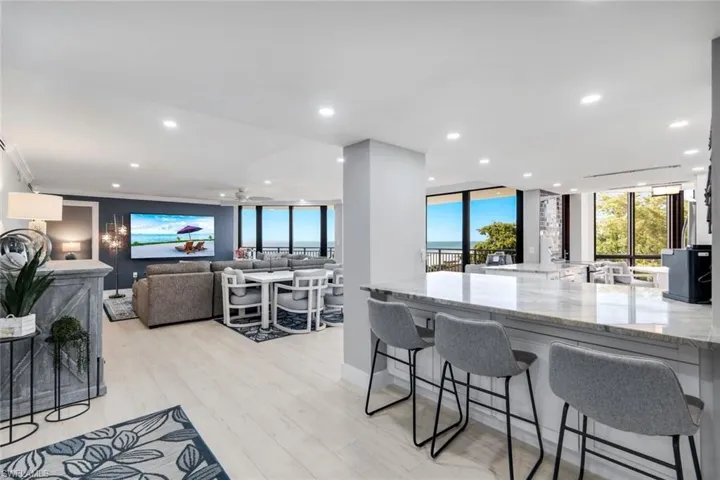 This open-concept living space features light-toned flooring, recessed lighting, and expansive windows offering views of the outdoors