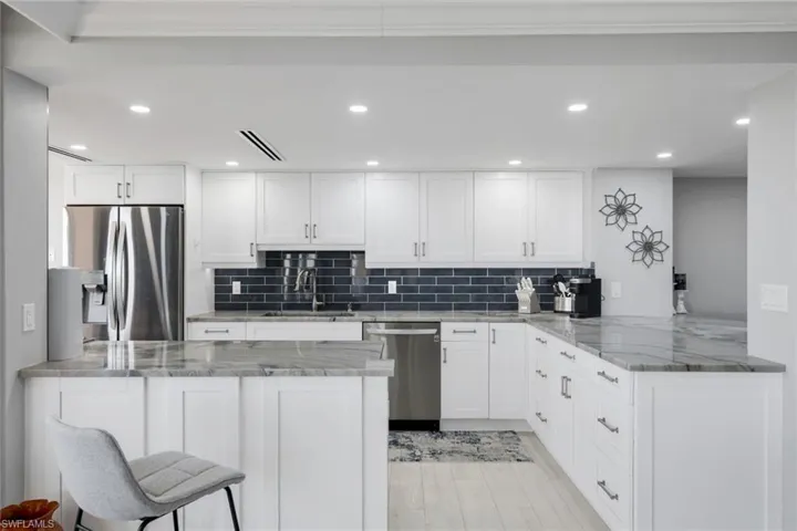 The kitchen showcases white cabinetry, a dark subway tile backsplash, and light-colored countertops