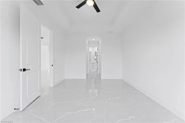 Empty room featuring ceiling fan and a tray ceiling