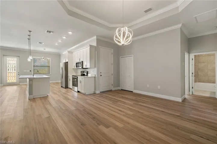 Kitchen featuring a chandelier, an island with sink, white cabinetry, open floor plan, and stainless steel appliances