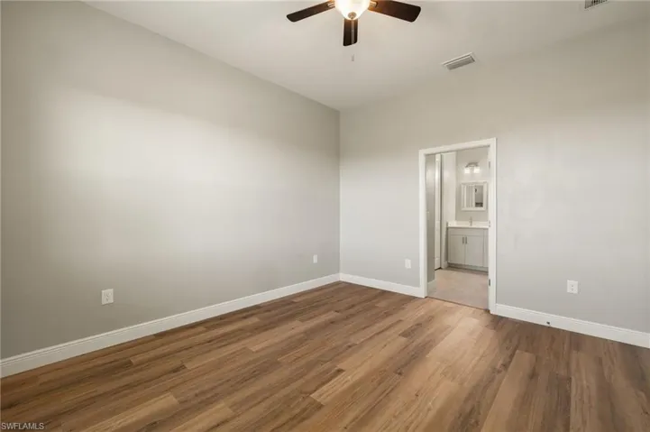 Unfurnished bedroom with wood finished floors, a ceiling fan, and ensuite bathroom