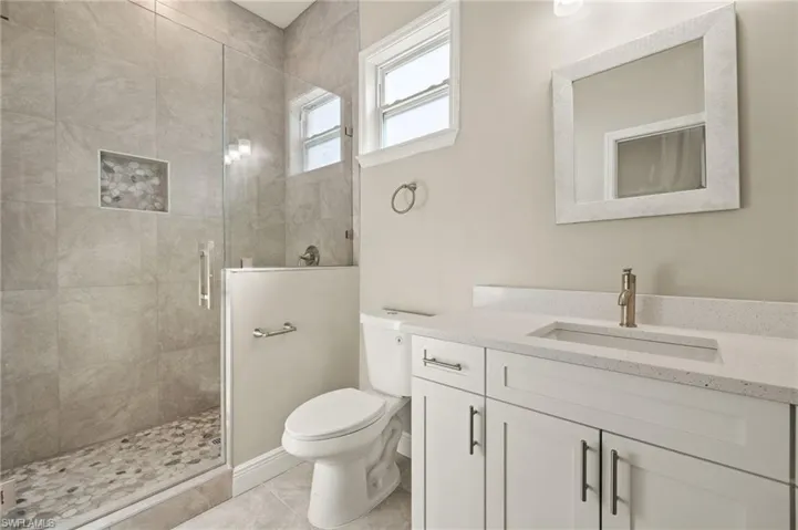 Bathroom featuring a shower stall, vanity, and light tile patterned flooring