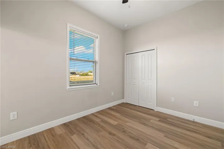Unfurnished bedroom with wood finished floors, a closet, and a ceiling fan
