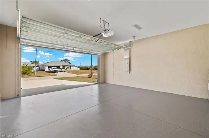Garage featuring a residential view, a textured wall, a garage door opener, and electric panel