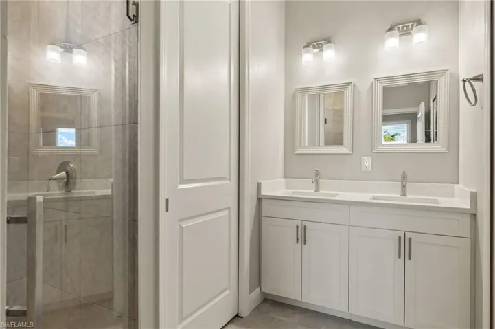 Full bathroom featuring double vanity and a stall shower