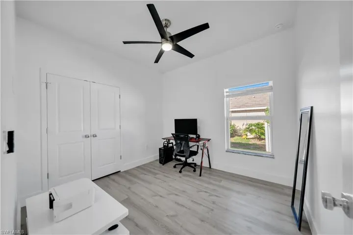 Office area with light wood-type flooring and ceiling fan