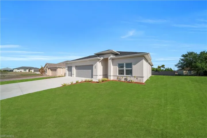 Prairie-style home featuring a front lawn, driveway, stucco siding, and a garage